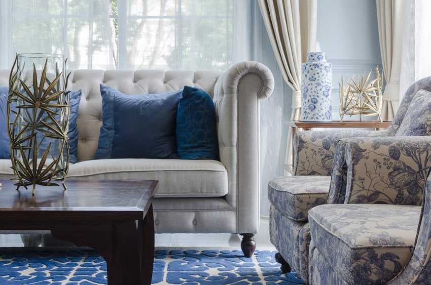 Close up of furniture pieces in living room with pleated couch and floral pattern chairs