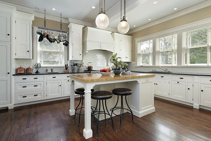 Country kitchen with white shaker cabinets, butcher block island and black granite countertops