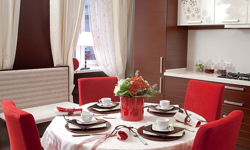 Красные спинки стульев в кухне с шоколадным гарнитуром