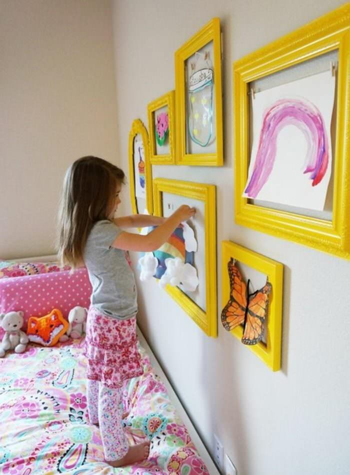 Девочка украшает комнату собственными рисунками